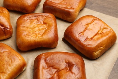 Photo of Many delicious baked patties on wooden table, closeup