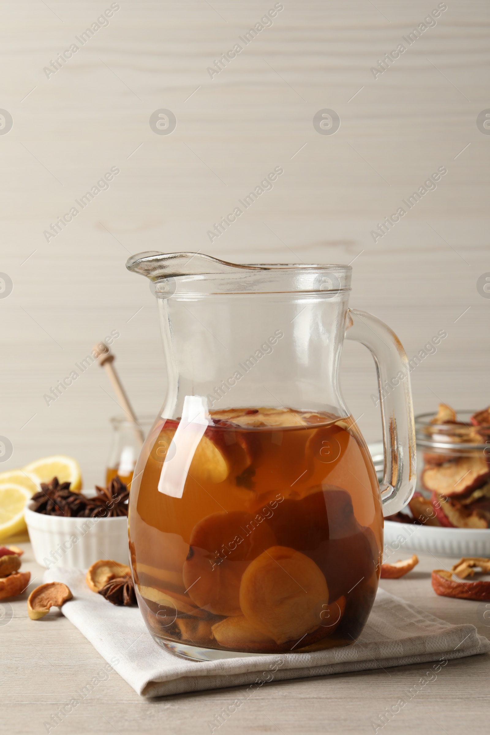 Photo of Delicious compote with dried fruits in glass jug on light wooden table