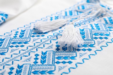 Photo of Beautiful white shirt with light blue Ukrainian national embroidery, closeup