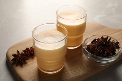 Photo of Glasses of delicious eggnog with anise on grey marble table, closeup