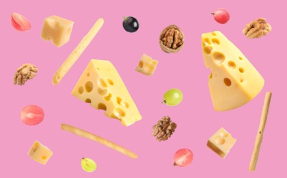 Image of Cheese, breadsticks, grapes and walnuts falling against pink background