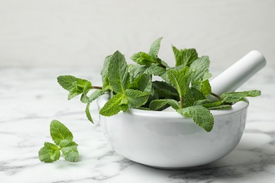 Mortar with fresh green mint and pestle on table