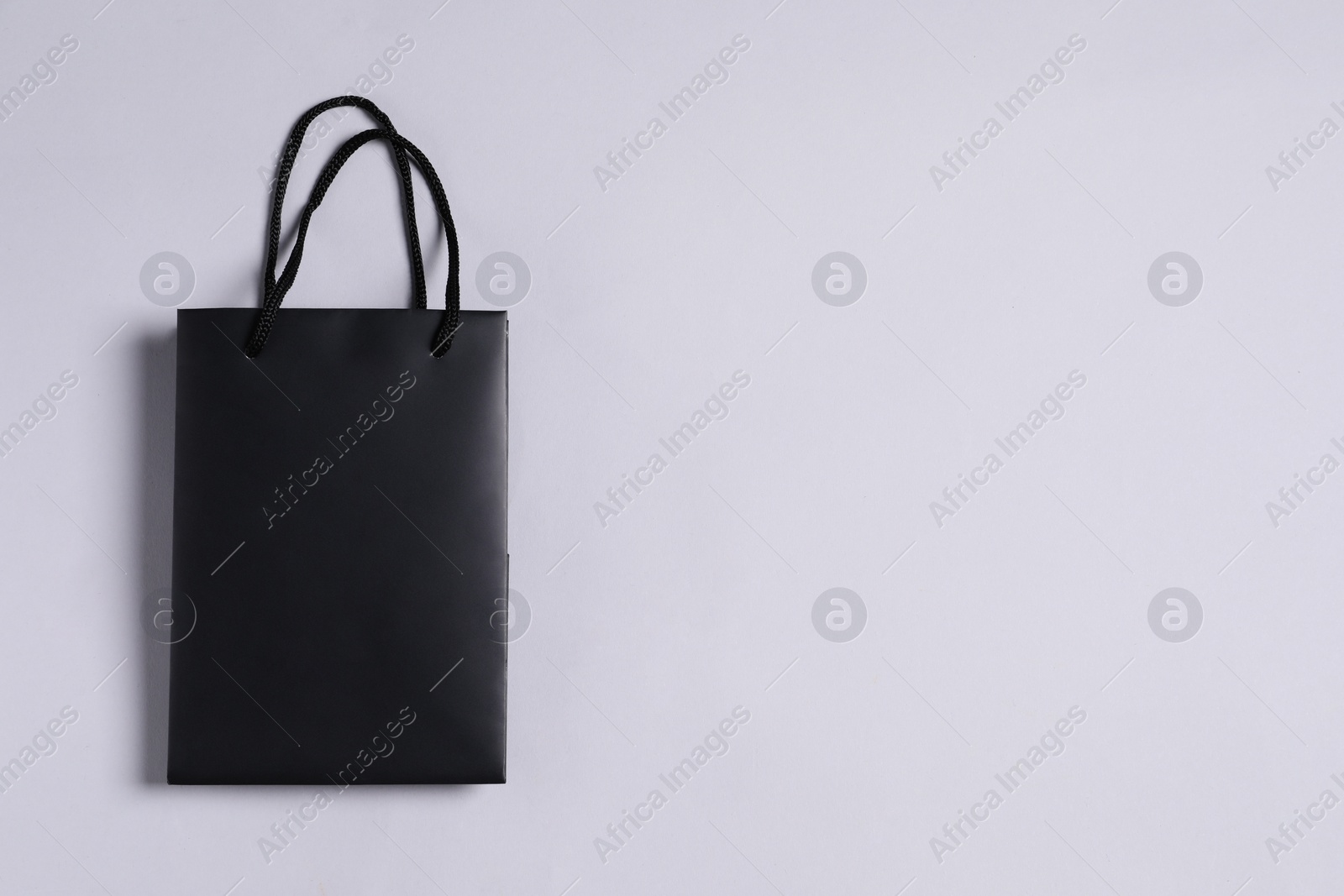 Photo of One black paper shopping bag on grey background, top view. Space for text