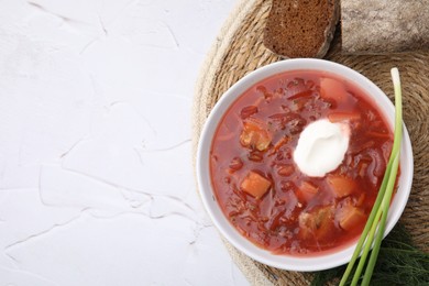 Tasty borscht with sour cream served on white textured table, flat lay. Space for text