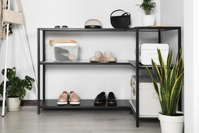 Photo of Black table with stylish shoes and accessories in hallway