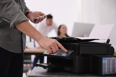 Photo of Employee using modern printer in office, closeup