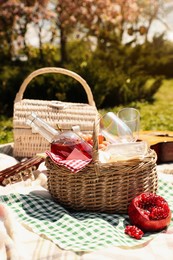 Photo of Delicious food and wine in picnic basket on blanket outdoors