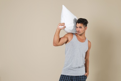 Young man with soft pillow on color background