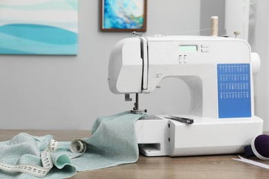 White sewing machine and cloth on wooden table indoors