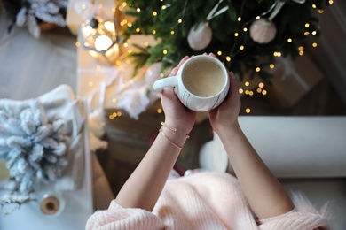 Photo of Woman with cup of cocoa in room decorated for Christmas, above view