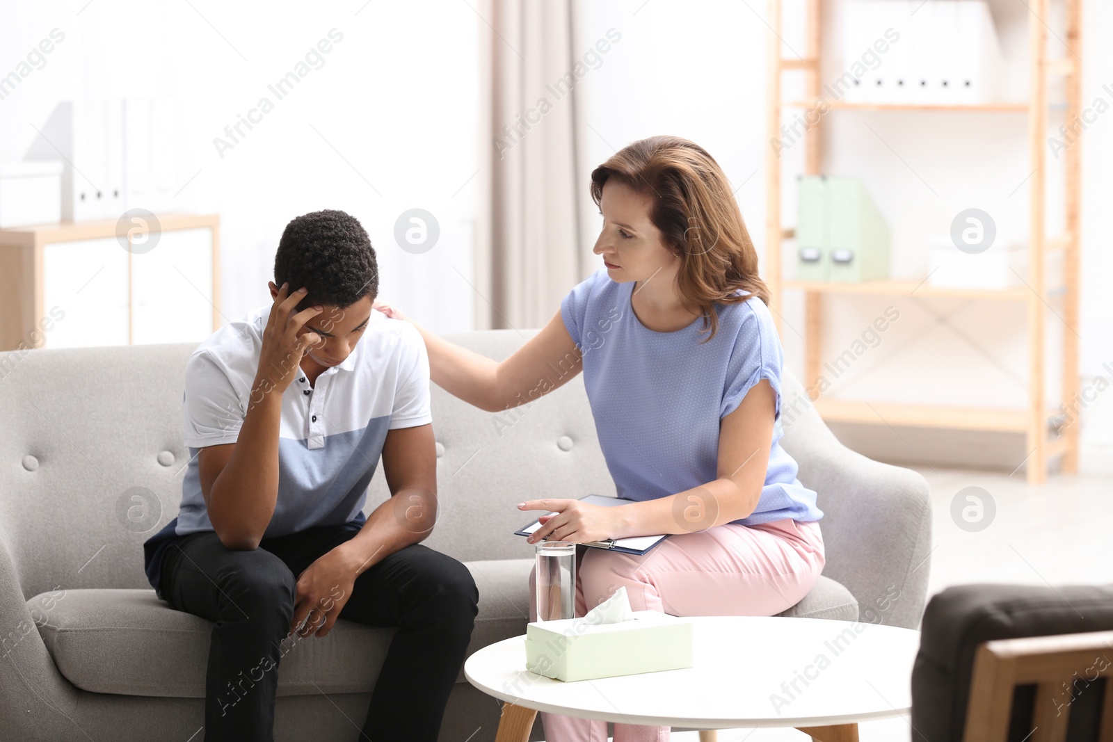 Photo of Psychotherapist working with African-American teenage boy in office