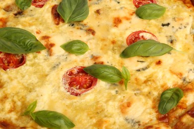 Photo of Delicious quiche with cheese, tomatoes and basil as background, closeup