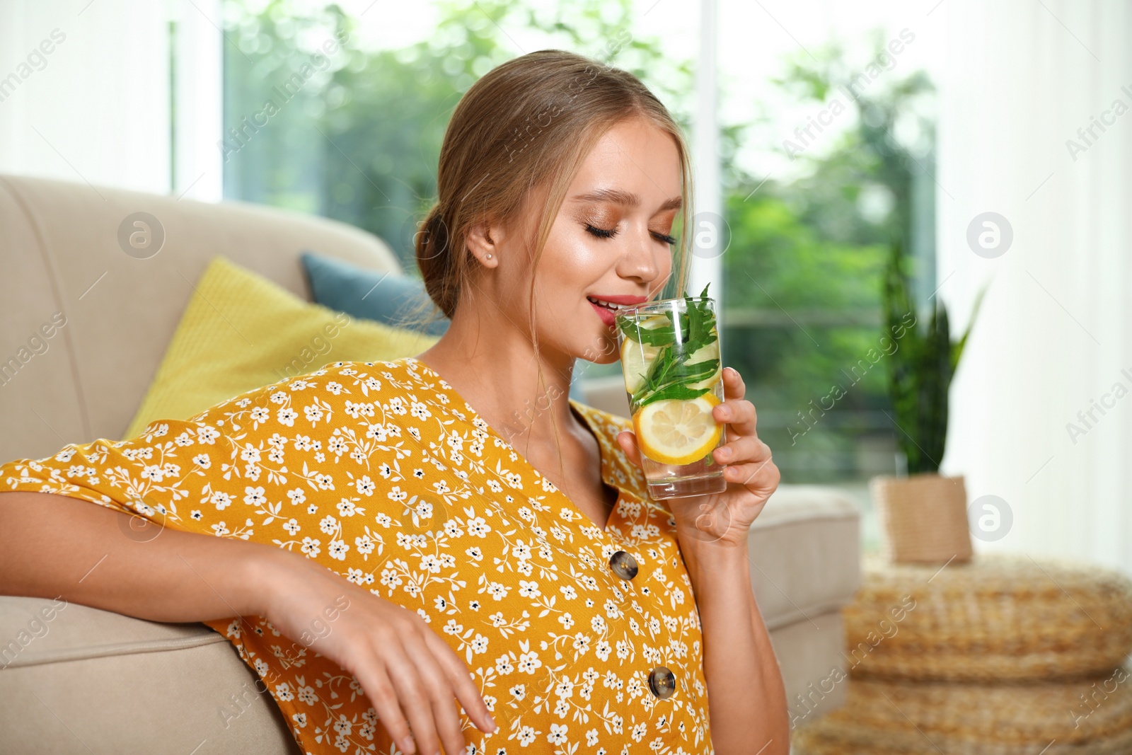 Photo of Young woman with glass of lemonade at home. Refreshing drink