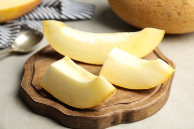 Wooden board with slices of ripe melon on table, closeup