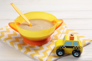 Photo of Baby food. Puree, spoon and toy on white wooden table