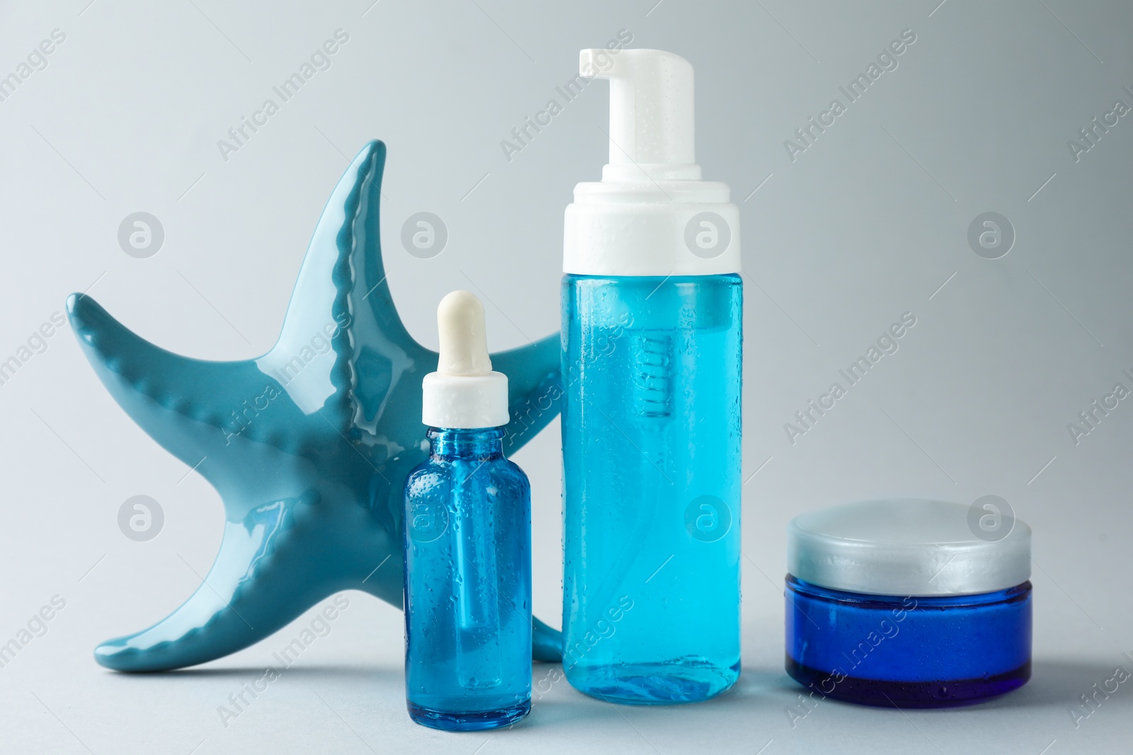 Photo of Set of cosmetic products and decorative starfish on light grey background