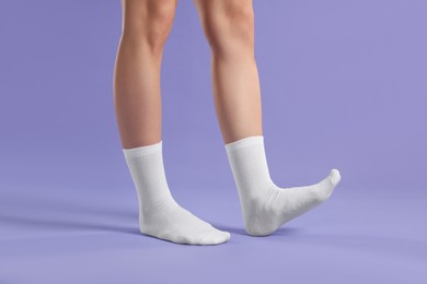 Photo of Woman in stylish white socks on violet background, closeup