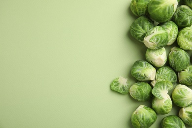 Fresh Brussels sprouts on green background, flat lay. Space for text