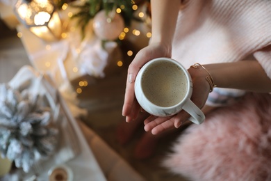 Photo of Woman with cup of cocoa in room decorated for Christmas, top view