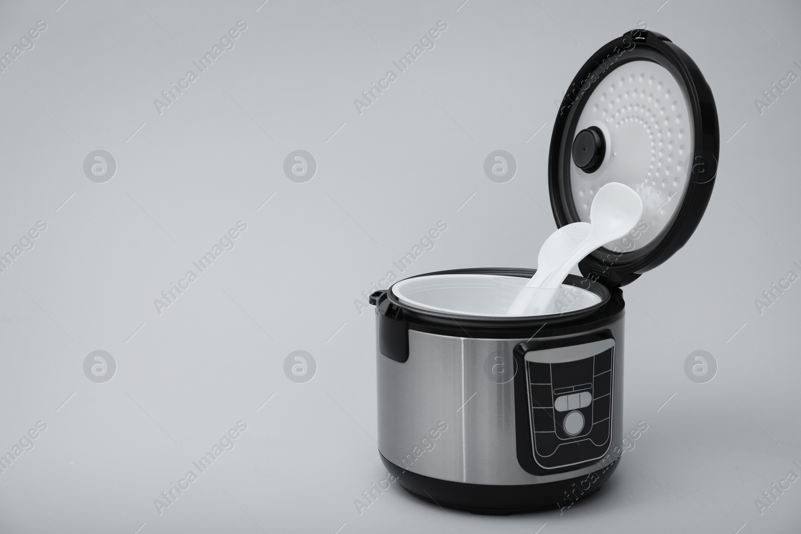 Photo of Modern electric multi cooker, parts and accessories on grey background. Space for text