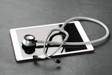 Photo of Modern tablet and stethoscope on black table