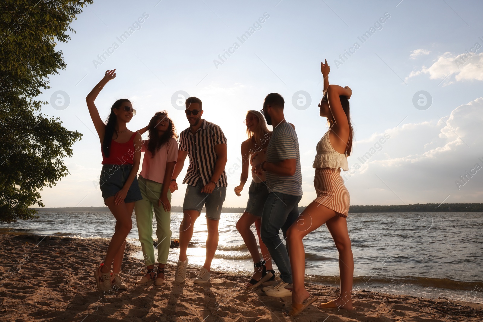 Photo of Group of friends having fun near river at summer party