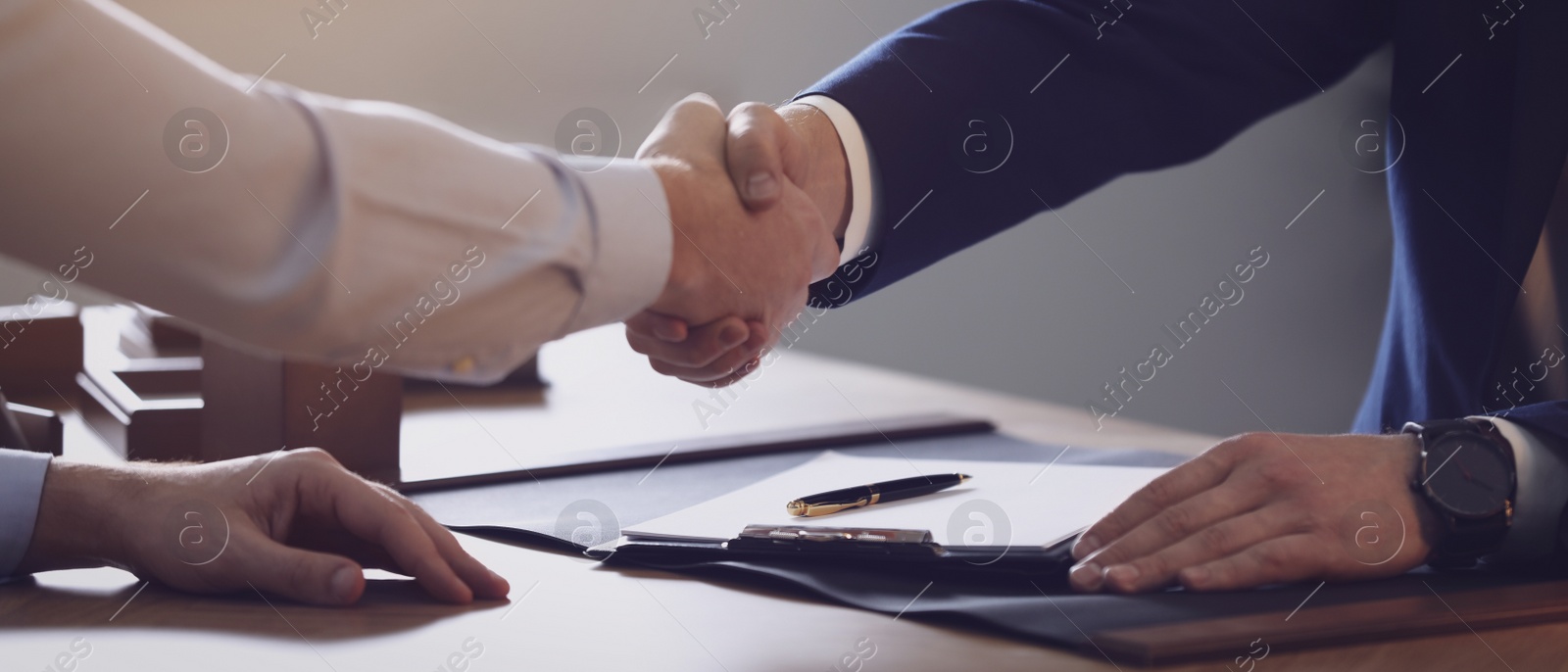 Image of Male lawyer shaking hands with client in office, closeup. Banner design