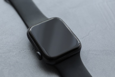 Photo of Stylish smart watch on grey stone table, closeup