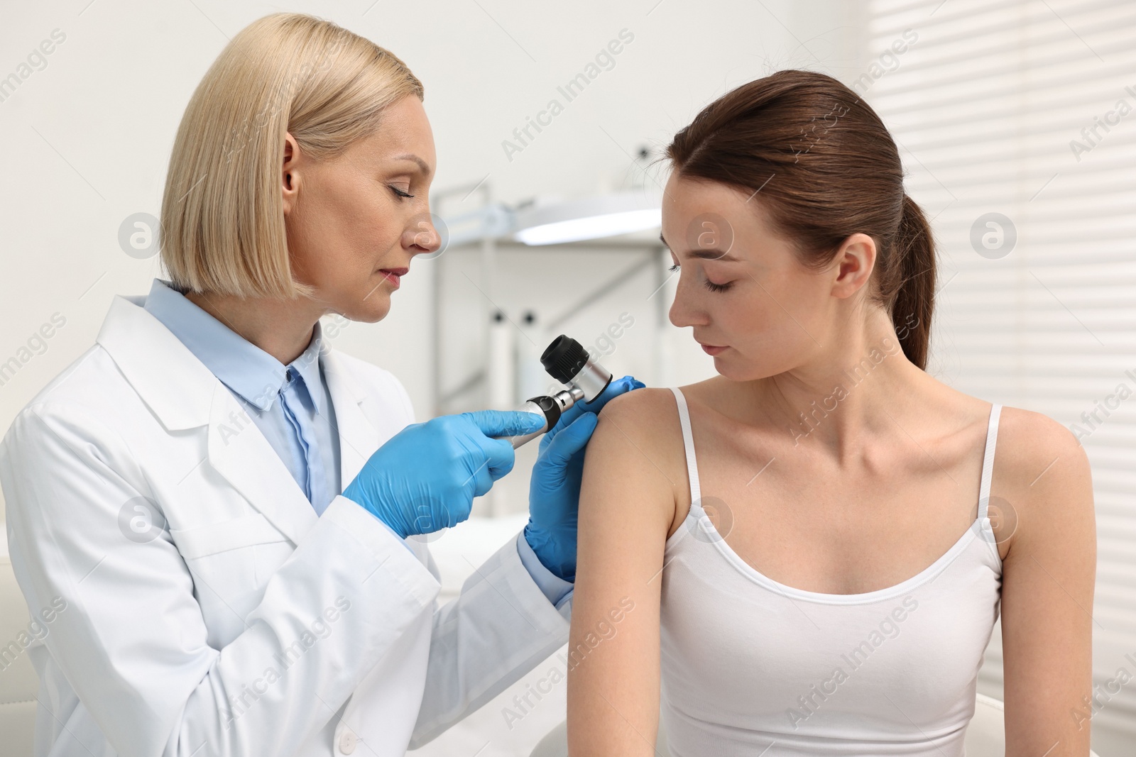 Photo of Dermatologist with dermatoscope examining patient in clinic