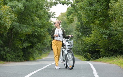 Photo of Beautiful woman in casual outfit with bicycle outdoors