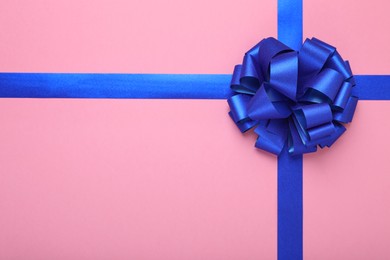 Photo of Blue ribbons with bow on pink background, top view. Space for text