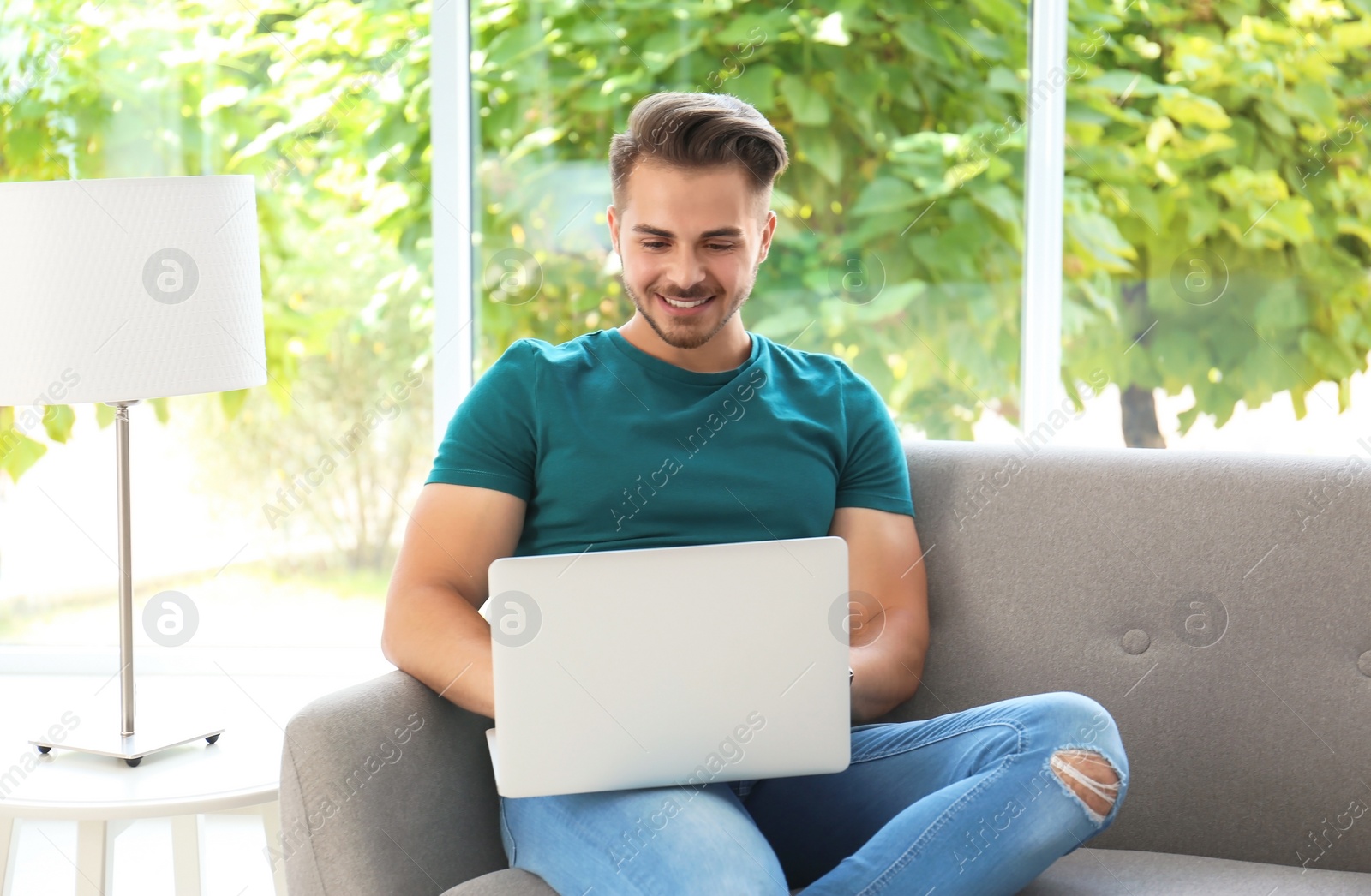 Photo of Man in casual clothes using laptop on sofa at home