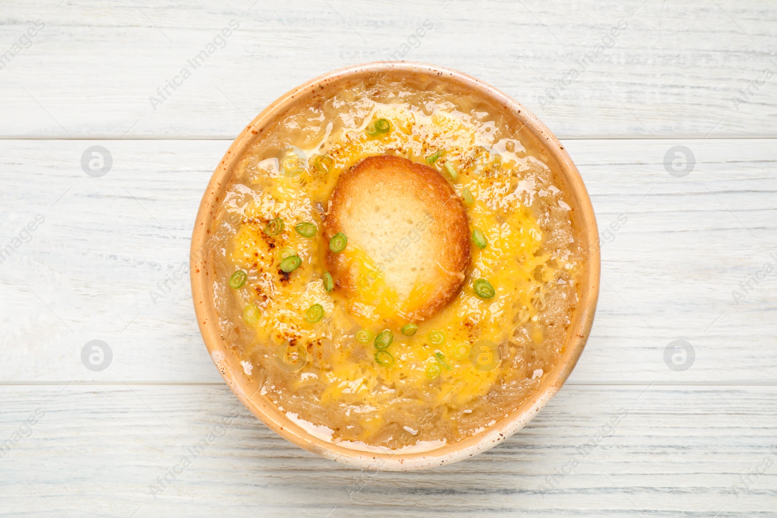 Photo of Tasty homemade french onion soup on white wooden table, top view