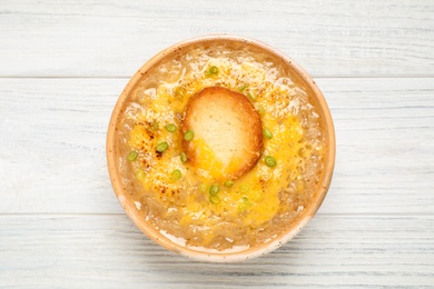 Photo of Tasty homemade french onion soup on white wooden table, top view