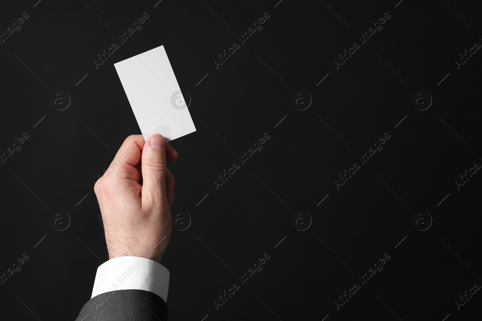 Photo of Businessman holding blank business card on black background, closeup. Space for text