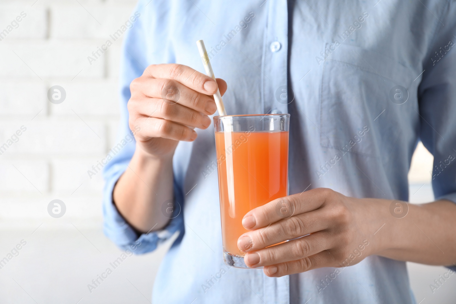 Photo of Woman holding glass of fresh juice with straw, closeup