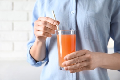 Photo of Woman holding glass of fresh juice with straw, closeup