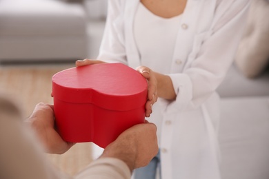 Man presenting gift to his beloved woman at home, closeup. Valentine's day celebration