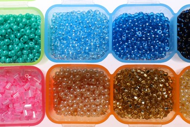 Photo of Plastic organizers with different beads on white background, top view