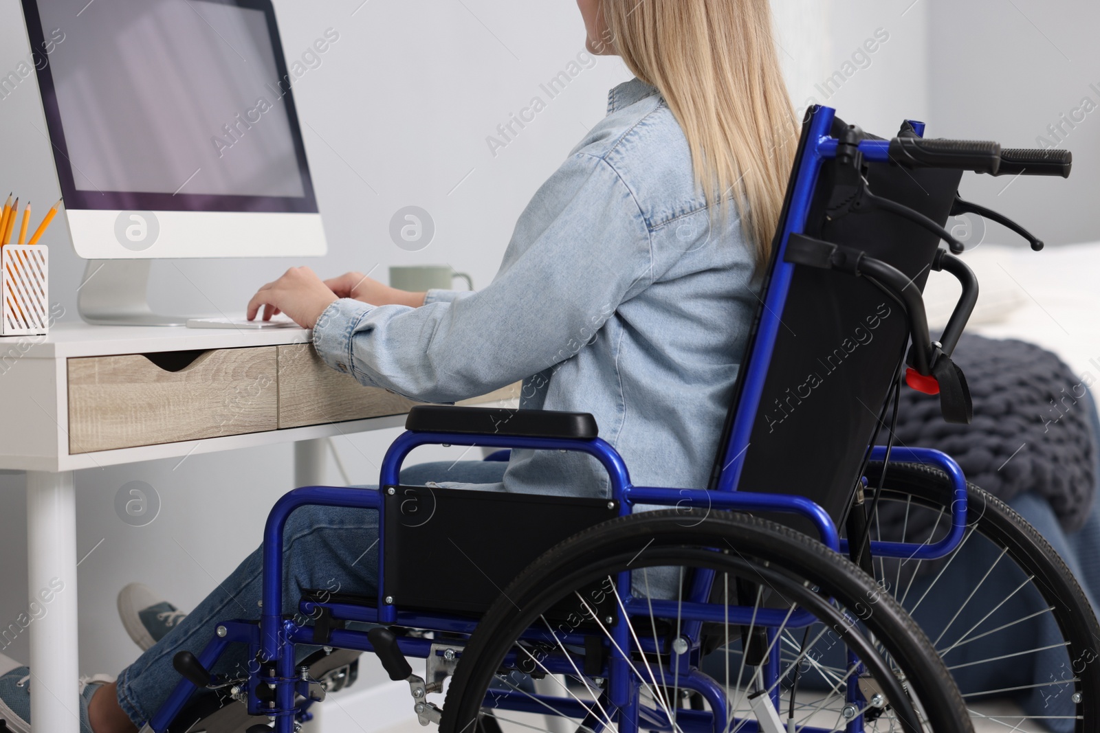 Photo of Woman in wheelchair using computer at home, closeup