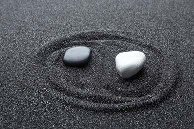 Yin Yang symbol made with stones on black sand. Zen concept