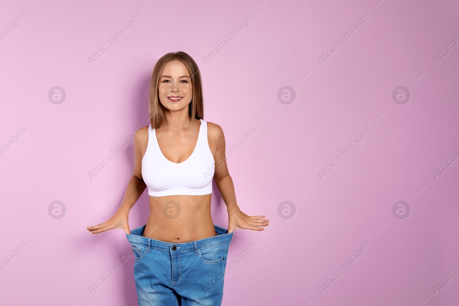 Photo of Slim woman in oversized jeans on color background. Healthy diet