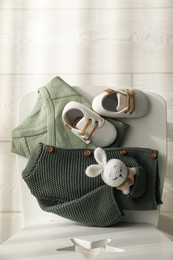 Baby clothes, shoes and toy on chair indoors, top view