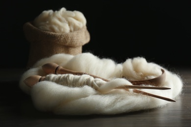 Photo of Soft white wool with spindles on wooden table