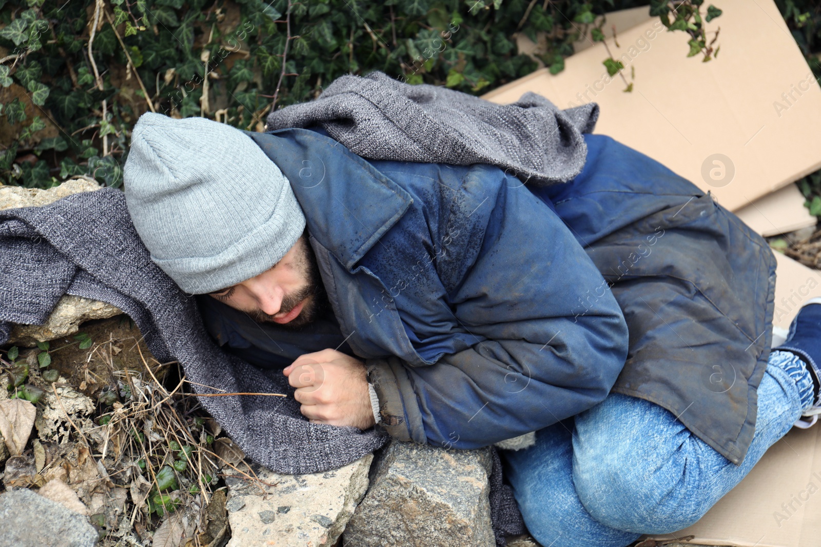 Photo of Poor homeless man lying on street in city