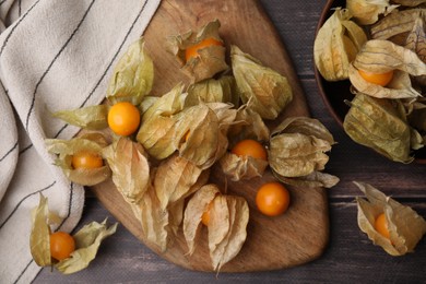 Photo of Ripe physalis fruits with calyxes on wooden table, flat lay