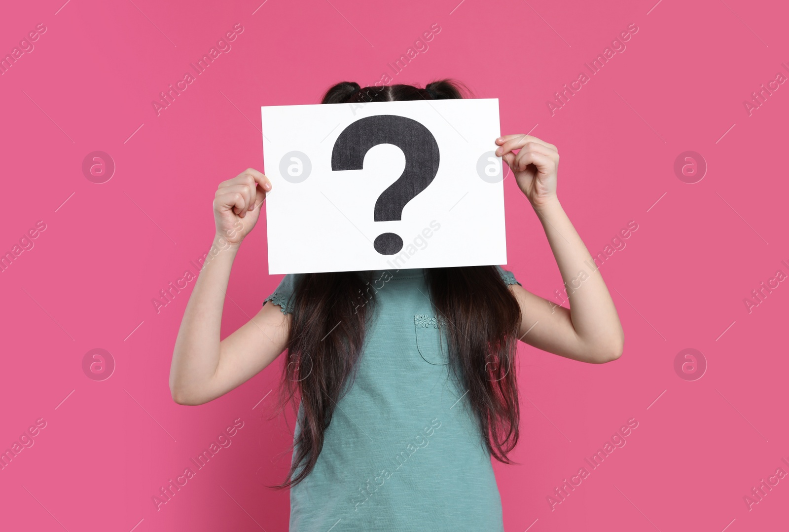 Photo of Girl holding sheet of paper with question mark on pink background