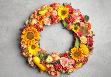 Beautiful autumnal wreath with flowers, berries and fruits on light grey background, top view. Space for text