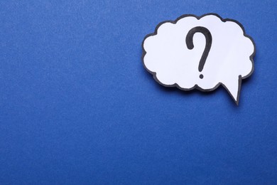 Paper speech bubble with question mark on blue background, top view. Space for text