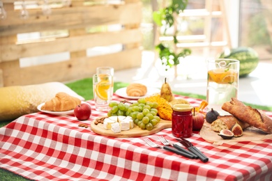 Different tasty food on picnic blanket at home